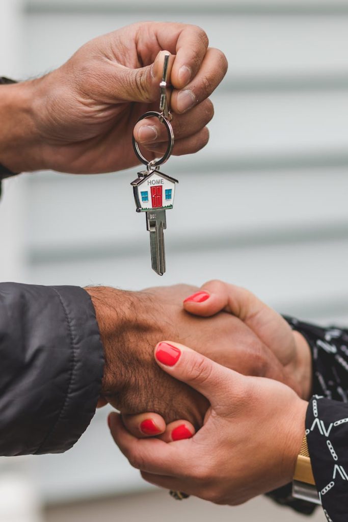 Close-up of a realtor handing over a house key to a new homeowner, symbolizing ownership and investment.